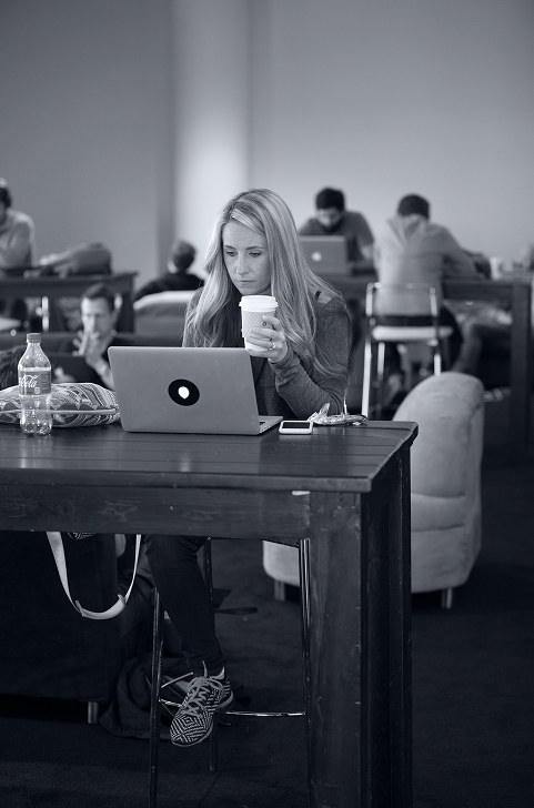 Female software engineer sitting at a laptop and holding a coffee cup