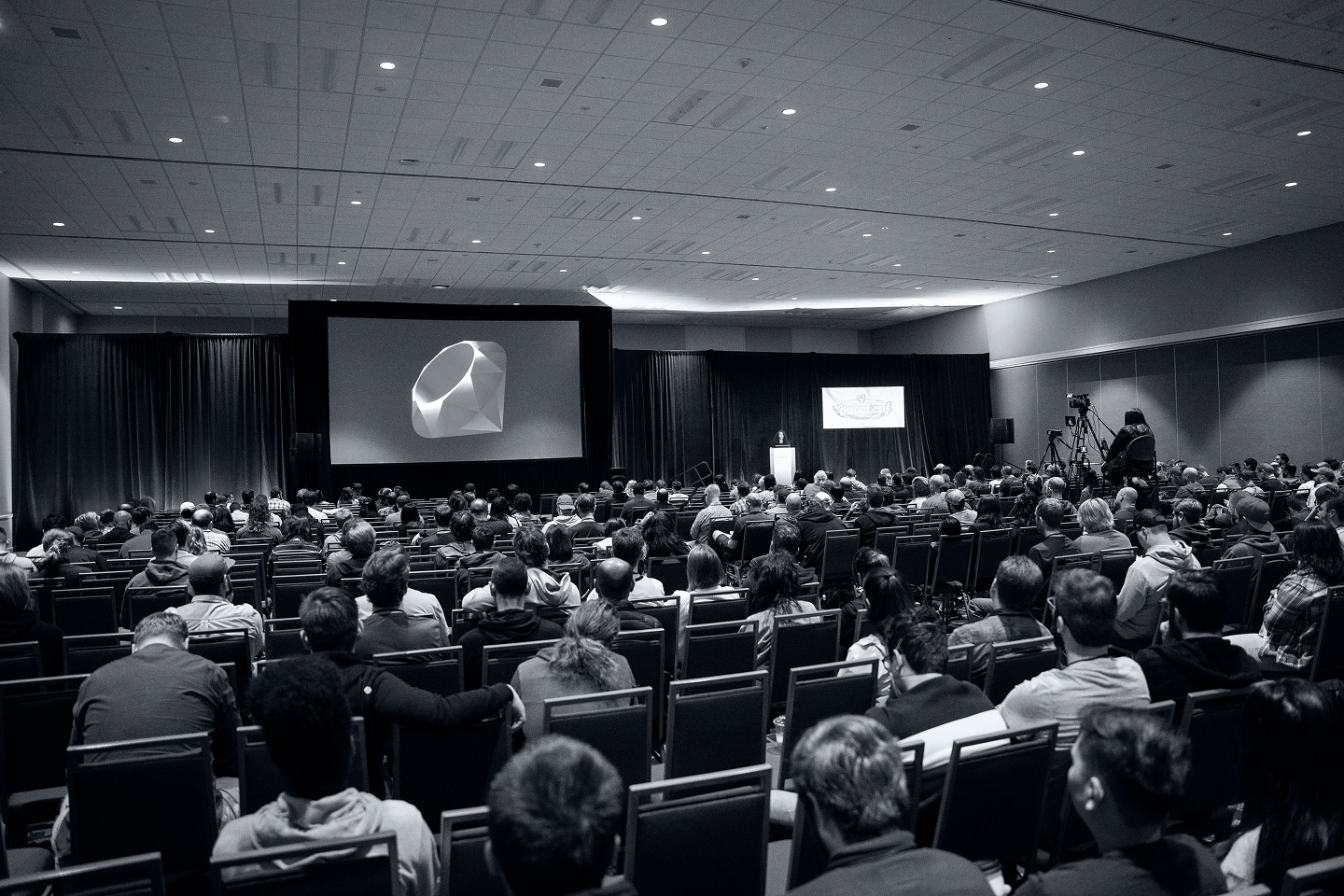 Conference room with numerous attendees and a main stage